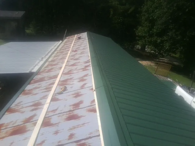 Old rusted panels beside newly installed green metal roofing — Wind Damage Roof Repair by Roofing Brothers in Mineral Point