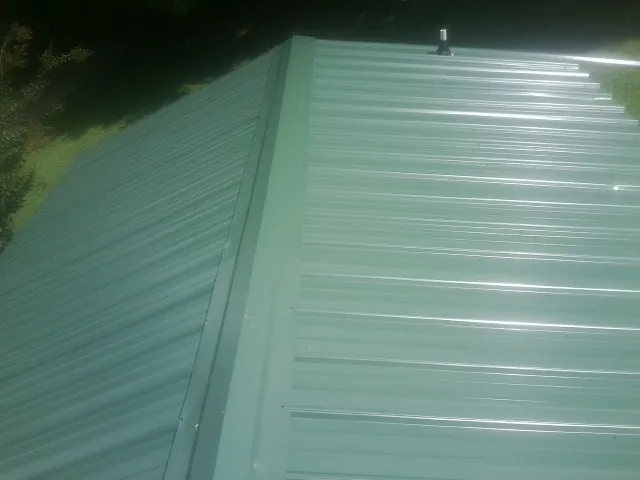 New green metal panels meeting at the ridge of a roof — Flat Roof Repair work by our crew in Mineral Point