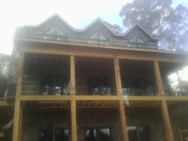 Dormers and porch framing on a large log home under construction — Roof Coating work by our crew in Mineral Point