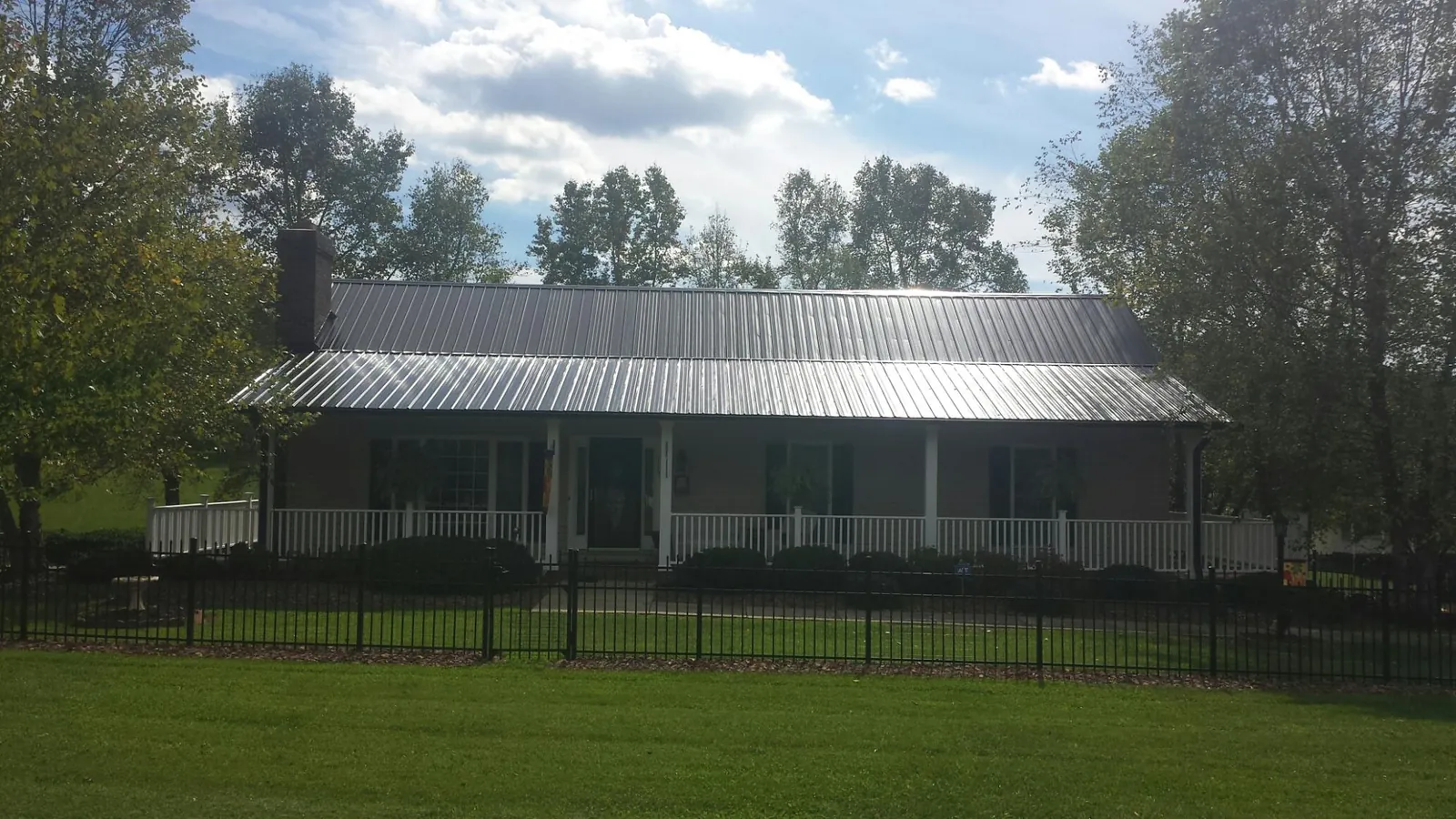 Gray metal roof on a brick ranch with a full width front porch — Gutter Guard Installation work by our crew in Mineral Point