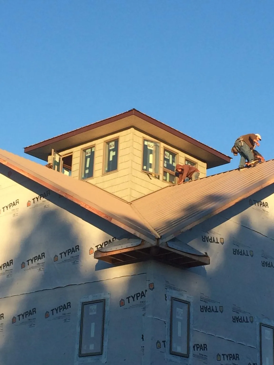Roofers working around a rooftop cupola on a new metal roof at sunset — Roof Waterproofing in Mineral Point by Roofing Brothers